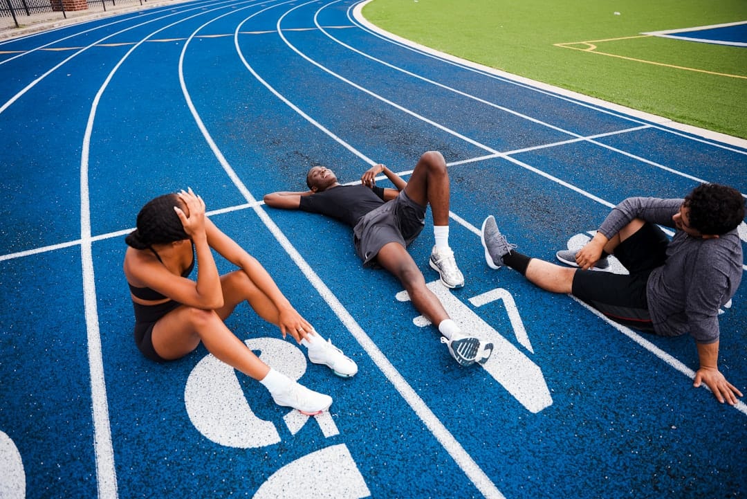 Athletes resting on a blue running track.